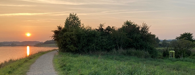 Landschaft an der Schlei im Sonnenuntergang mit einem Wind-Telefon