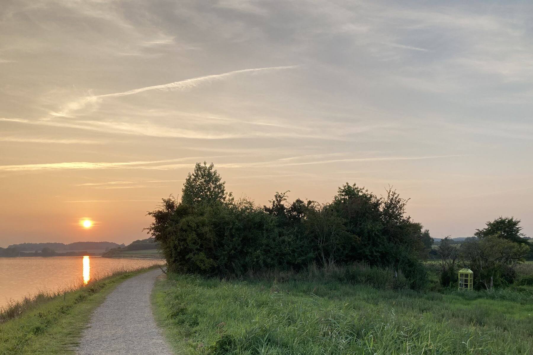Sonnenuntergangstimmung mit einer grünen Telefonzelle